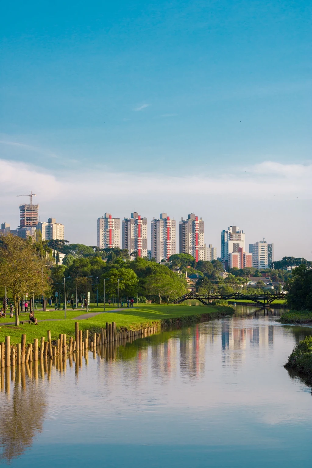 Vista de Curitiba com parque, lago e skyline ao fundo